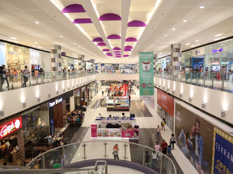 巴科羅 SM City 購物中心的挑高中庭，兩側是店面和餐廳，中央展示區周圍掛著紅燈籠