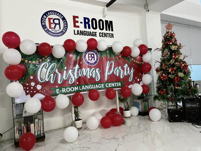 e-Room 語言學校的聖誕布置：校徽牆下是紅白氣球圍起的 Christmas Party 布條，右邊有一棵裝飾好的聖誕樹